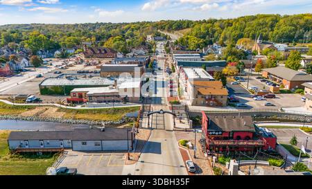 Blick aus der Vogelperspektive auf die Innenstadt von Algonquin Illinois entlang des Fox River mit Straßenlandschaften am Flussufer, Brückenüberquerung, Yachthafen und lokalen Unternehmen. Stockfoto