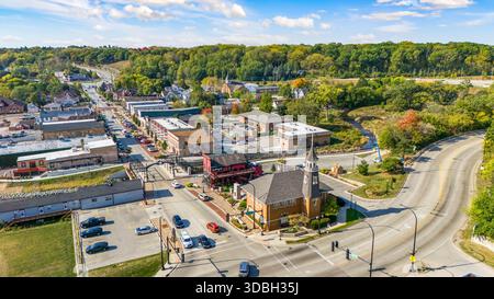 Blick aus der Vogelperspektive auf die Innenstadt von Algonquin Illinois entlang des Fox River mit Straßenlandschaften am Flussufer, Brückenüberquerung, Yachthafen und lokalen Unternehmen. Stockfoto