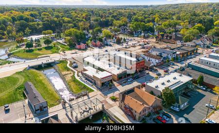 Blick aus der Vogelperspektive auf die Innenstadt von Algonquin Illinois entlang des Fox River mit Straßenlandschaften am Flussufer, Brückenüberquerung, Yachthafen und lokalen Unternehmen. Stockfoto