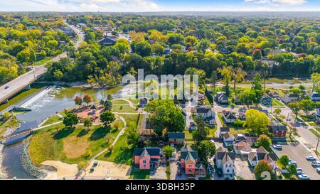 Blick aus der Vogelperspektive auf die Innenstadt von Algonquin Illinois entlang des Fox River mit Straßenlandschaften am Flussufer, Brückenüberquerung, Yachthafen und lokalen Unternehmen. Stockfoto