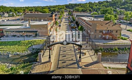 Blick aus der Vogelperspektive auf die Innenstadt von Algonquin Illinois entlang des Fox River mit Straßenlandschaften am Flussufer, Brückenüberquerung, Yachthafen und lokalen Unternehmen. Stockfoto