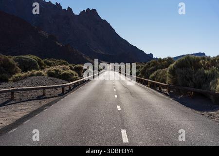 Gerade Straße TF 21 mit Auto durch vulkanische Wüstenlandschaft und zerklüftete Berge im Teide Nationalpark, Teneriffa, Kanarische Inseln, Spanien. Stockfoto