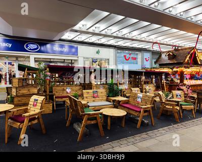 Manchester, Großbritannien - 19. November 2025: Gemütliche Holzmöbel auf einem festlichen Markt mit Stühlen, Kissen und dekorativen Lichtern in Manchester. Stockfoto