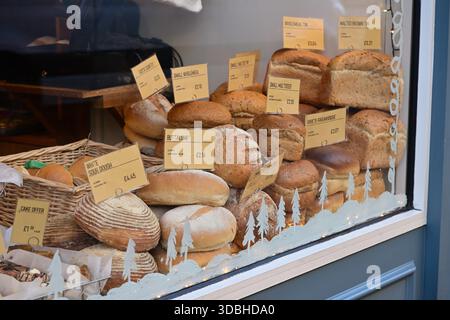 Lichfield, Großbritannien - 10. Dezember 2025: Schaufensteranzeige für die handwerkliche Bäckerei mit verschiedenen Broten und Preisen Stockfoto