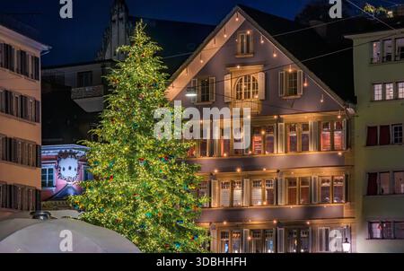Festliche nächtliche Szene mit einem großen beleuchteten Weihnachtsbaum neben einem charmanten historischen Gebäude am Münsterplatz in Zürich, Schweiz Stockfoto