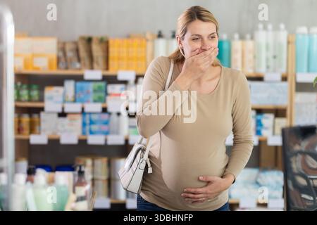 Schwangere Frau besucht Apotheke und leidet unter Übelkeit Stockfoto