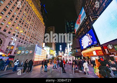 Times Square in der Nacht mit beleuchteter amerikanischer Flagge, Menschenmassen und hellen Werbeflächen in New york Stockfoto
