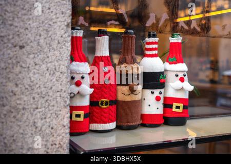 Eine festliche Ausstellung von Weinflaschen mit Strickbezügen im Weihnachtsmotiv, mit Weihnachtsmann, Rentier und Schneemann, die Weihnachten spi zeigen Stockfoto