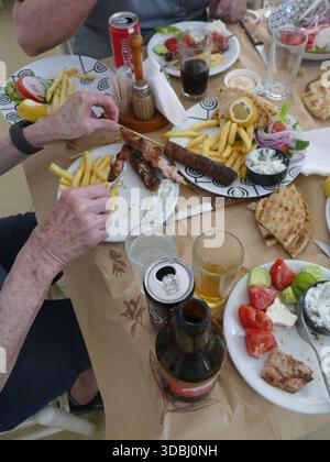MEGALOPOLIS, GRIECHENLAND - 15. MAI 2025 - Touristen essen in einem griechischen Restaurant zu Mittag mit Souvlaki, Pommes frites, Pitabrot und griechischem Salat Stockfoto