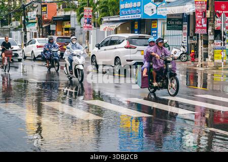 Vietnamesen Motorradfahrer auf Motorrädern und Autos fahren während der Regenzeit im Winter in Nha Trang in Asien bei starkem Regen die Straße entlang. Nha Trang, Vietnam - 13. Dezember 2024 Stockfoto