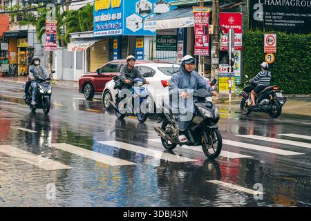 Vietnamesen Motorradfahrer auf Motorrädern und Autos fahren während der Regenzeit im Winter in Nha Trang in Asien bei starkem Regen die Straße entlang. Nha Trang, Vietnam - 13. Dezember 2024 Stockfoto