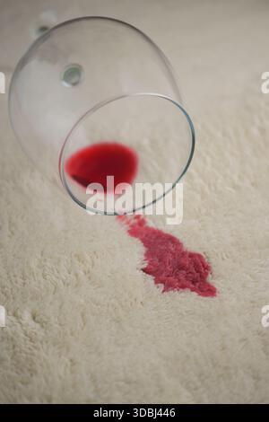 Rote Flüssigkeit aus Glas auf weiße Teppichoberfläche Stockfoto