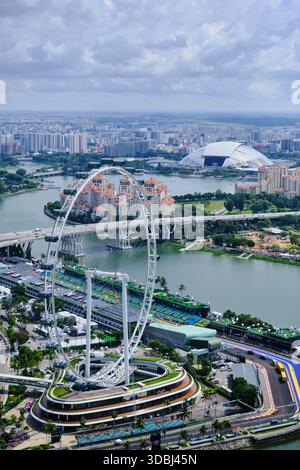 Atemberaubende vertikale Hochwinkelansicht mit dem legendären Singapore Flyer vor dem dichten, modernen Stadtbild und dem Kallang River. Stockfoto