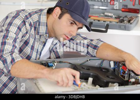 Reparaturarbeiter, der an einer Waschmaschine arbeitet Stockfoto