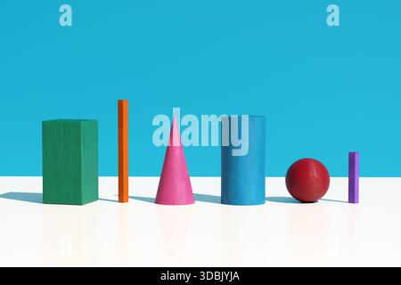 Minimalistische Komposition mit farbenfrohen geometrischen Holzformen auf weißer Oberfläche vor einem leuchtend blauen Hintergrund Stockfoto