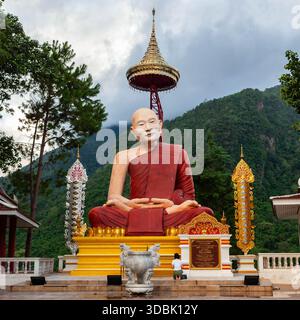 Chiang Dao, Thailand – 12. Juni 2024: Frau betet vor der Statue eines Mönchs, des Großen Meisters Narasabho Mahathera, Wat Phra That Doi Chiang Dao. Stockfoto