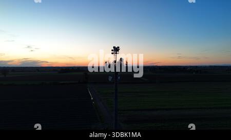 Mobilfunkturm, der die Telekommunikation und Mobilfunknetzkonnektivität in der weiten landwirtschaftlichen Landschaft des Potals in der Abenddämmerung ermöglicht, mit dem cr Stockfoto