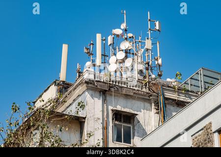 Handymasten auf einem Hausdach. Viele Richtantennen des 5G-Mobilfunknetzes auf dem Dach eines Wohngebäudes. 5G- und 4G-Mobilfunkmasten Stockfoto