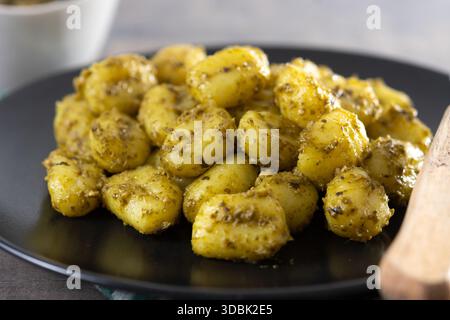 Gnocchi mit Pesto-Sauce serviert auf schwarzem Teller Stockfoto