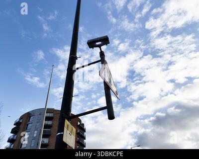 Eine moderne Straßenszene in Manchester mit einem hohen Laternenpfahl, Verkehrsschild und Wohngebäuden unter hellem Himmel. Stockfoto