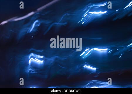 Ein energetischer abstrakter Hintergrund mit blauen Lichtstreifen, die einem Blitz oder Elektrizität auf einem dunklen Hintergrund ähneln. Stockfoto