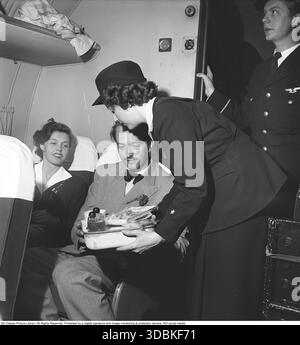 Flugreisen in den 1950er Jahren Das weibliche Mitglied der Crew steht mitten im Flugzeug und serviert den Passagieren Kaffee und Sandwiches. 1950 Kristoffersson Ref. AZ58-1 Stockfoto
