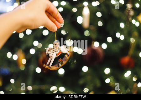 Hand hält weihnachtspferd Spielzeug auf dem Hintergrund des weihnachtsbaums mit goldenen Lichtern. Symbol 2026. Frohes Neues Jahr! Kopierbereich Stockfoto