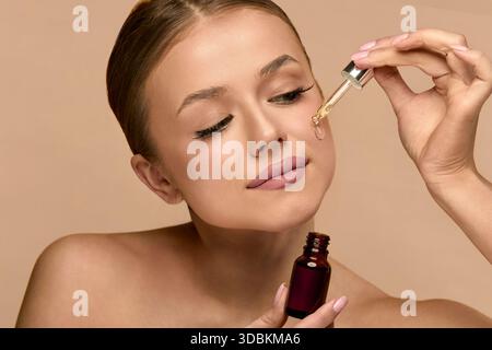Nahaufnahme einer jungen Frau mit Gesichtsserum. Frau mit Tropfer und Gesichtskinpflege Kosmetik für Schönheit, Hydration oder Öl Behandlung für gesundes Gesicht Stockfoto