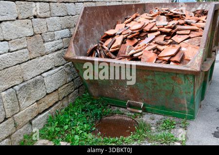 Zertrümmerte Dachziegel im Bauschutt-Container Stockfoto