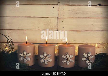 Drei brennende Adventskerzen. Brennende Kerzen für den dritten Advent. Einfache weihnachtsdekoration mit drei Kerzen vor einer hellen Holzdiele mit Platz für Text. Stockfoto