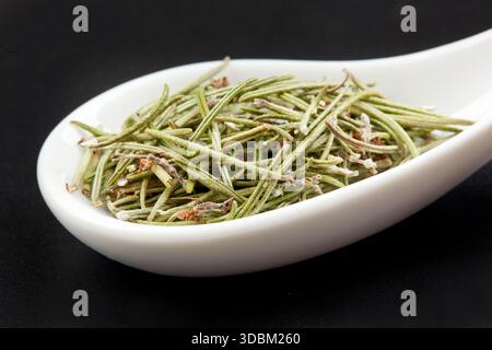 Rosmarin in weißen Löffel am schwarzen Tisch Stockfoto
