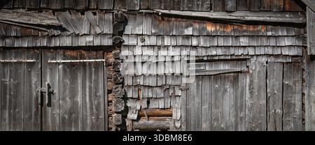 Ansicht einer verwitterten grauen Wand mit Holzstruktur. Alte Scheunenfassade aus Schindeln und Balken. Außenwand einer alten Kabine. Stockfoto
