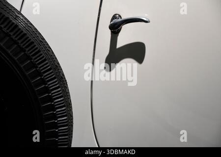 Einfacher verchromter Türgriff am Oldtimer an weißer Fahrzeugtür Stockfoto