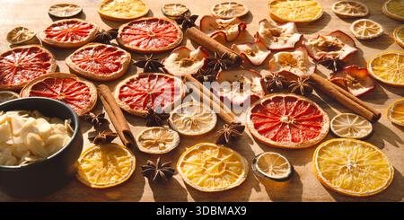 Verschiedene getrocknete Früchte und Gewürze für den Winter und die Weihnachtszeit. In Scheiben geschnittene getrocknete Zitrusfrüchte, Apfelringe mit Zimtstangen und Sternanis auf Holz. Vorbereitungen für die weihnachtsfeier. Stockfoto