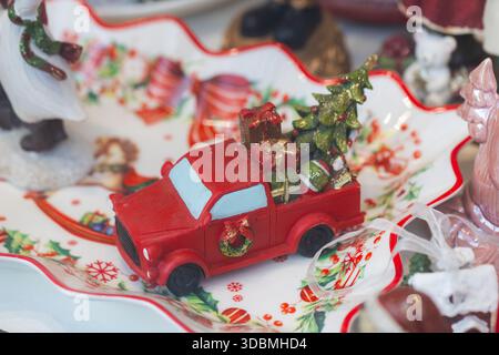 Roter weihnachtlicher Pick-up-Truck, Miniatur mit Weihnachtsbaum und Geschenken auf festlichem Teller Stockfoto