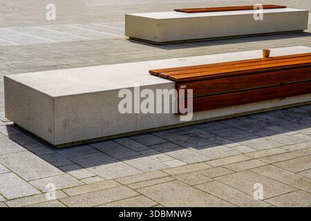 Köln, Deutschland, zwei moderne Bänke in einem Innenhof, auf der Vorderbank steht eine Kaffeetasse, Plastikmüll, Stockfoto
