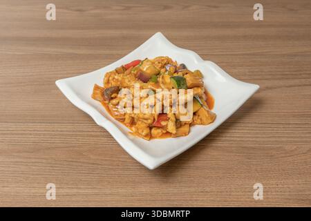 Authentisches Kung Pao Hühnchen mit gerösteten Erdnüssen, ganzen getrockneten Chilis und dunkler Sojasauce, serviert in einer Keramikschale mit gedämpftem Reis Stockfoto