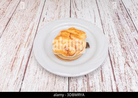 Mandarinen-Zitronenkuchen mit einer lebendigen Orangenquark-Füllung, garniert mit karamelisierten Mandarinensegmenten und italienischem Baisué Stockfoto