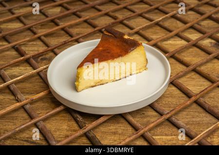 Einzelne Scheibe Käsekuchen mit verdauungsfördernder Keksbasis und Kirschmarmelade, serviert mit einer Schaufel Vanilleeis und weißer Schokolade Stockfoto