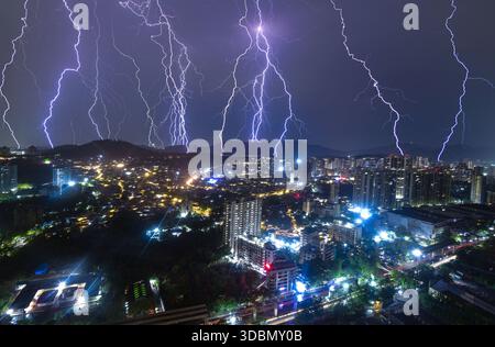 Blick auf elektrisierende Blitze, die den Nachthimmel über der Stadtlandschaft mit hellen Lichtern unter der Stadt beleuchten, Mumbai, Maharashtra, Indien. Stockfoto