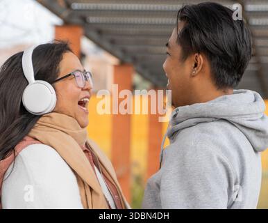 Multiethnisches asiatisches Paar lacht zusammen im Freien bei zwanglosen Gesprächen Stockfoto