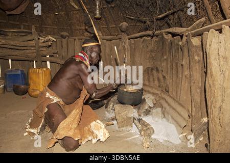 Nyangatom-Frau, die Sorghum-Hirse-Brei über einem Holzfeuer in ihrer Hütte zubereitete, ethnische Gruppe der Nyangatom, auch Bume genannt, Süd-Omo-Tal, Süd-Äthiopien Stockfoto