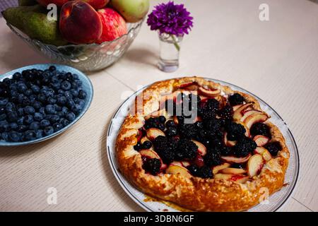 Frisch gebackene Torte mit Äpfeln und Beeren, auf einem Teller mit einer Obstschale in der Nähe von Tarnow Polen. Stockfoto
