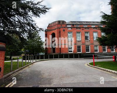 Historisches Trafford Town Hall Campus-Gebäude aus rotem Backstein in Manchester, Großbritannien, mit geschwungener Auffahrt und Bäumen. Stockfoto