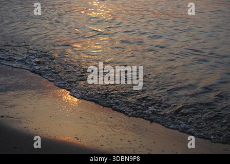 Wasser und Sand am Strand bei Sonnenaufgang an der Ostsee Stockfoto