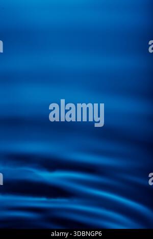 264.Abstract Nahaufnahme einer wasserähnlichen Oberfläche mit glatten Wellenmustern und blauem Verlauf. Dunkle Töne am unteren Rand werden zu hellblau und Grau am oberen Rand, Crea Stockfoto
