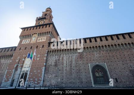 MAILAND, ITALIEN, 06.19.2025: Eindrucksvolle Fassade der mittelalterlichen Festung mit einem zentralen Glockenturm, dekorativen Mosaiken und Steinreliefs. Breite, sonnendurchflutete Kurve Stockfoto