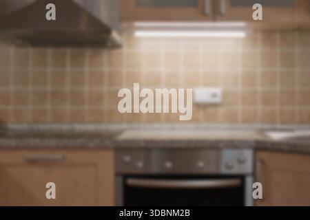 Klassische Küche mit verschwommenem Interieur. Braune Fliesen, Backofen und Dunstabzugshaube. Stockfoto