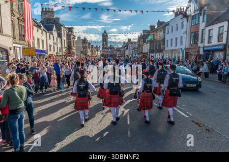Die Zuschauer beobachten eine Beltane-Zeremonie, während Tänzer in Kilts unter festlichen Bannern entlang der Peebles High Street marschieren. Stockfoto