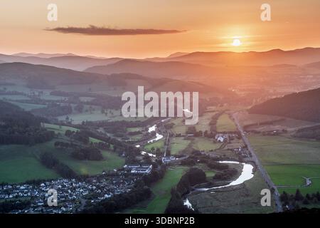 Blick aus der Vogelperspektive auf das Cardrona-Tal bei Sonnenuntergang in Neuseeland mit gewundenen Fluss, Feldern, Hügeln und einem kleinen Dorf. Stockfoto